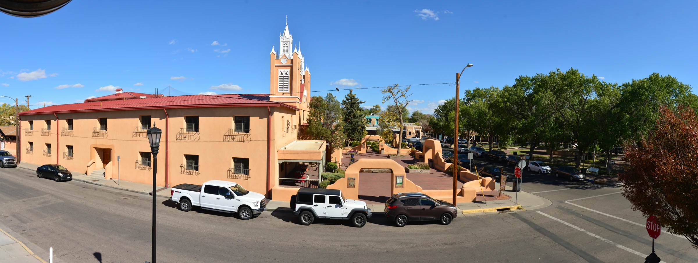 San Felipe de Neri Church beside the Old Town plaza, with parked vehicles along the street