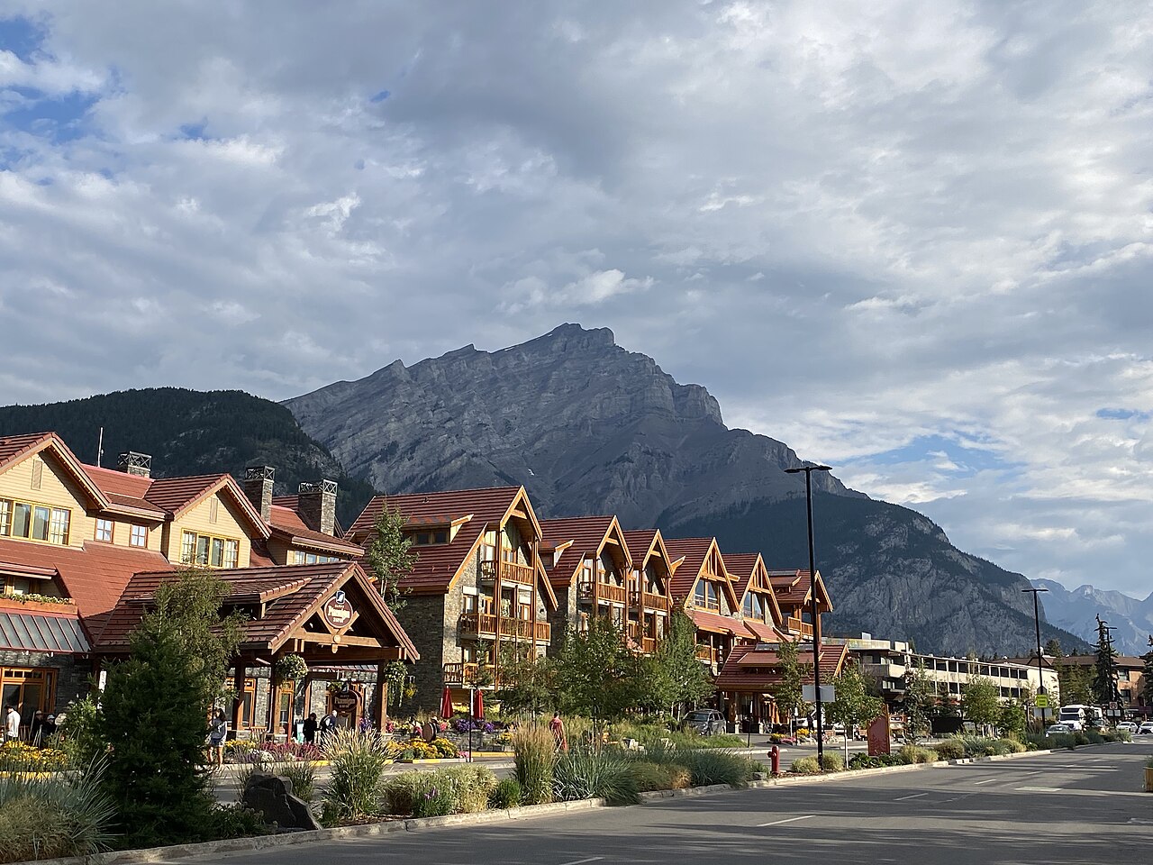 Lodge-style buildings on Banff Avenue with Mount Norquay behind under a cloudy sky