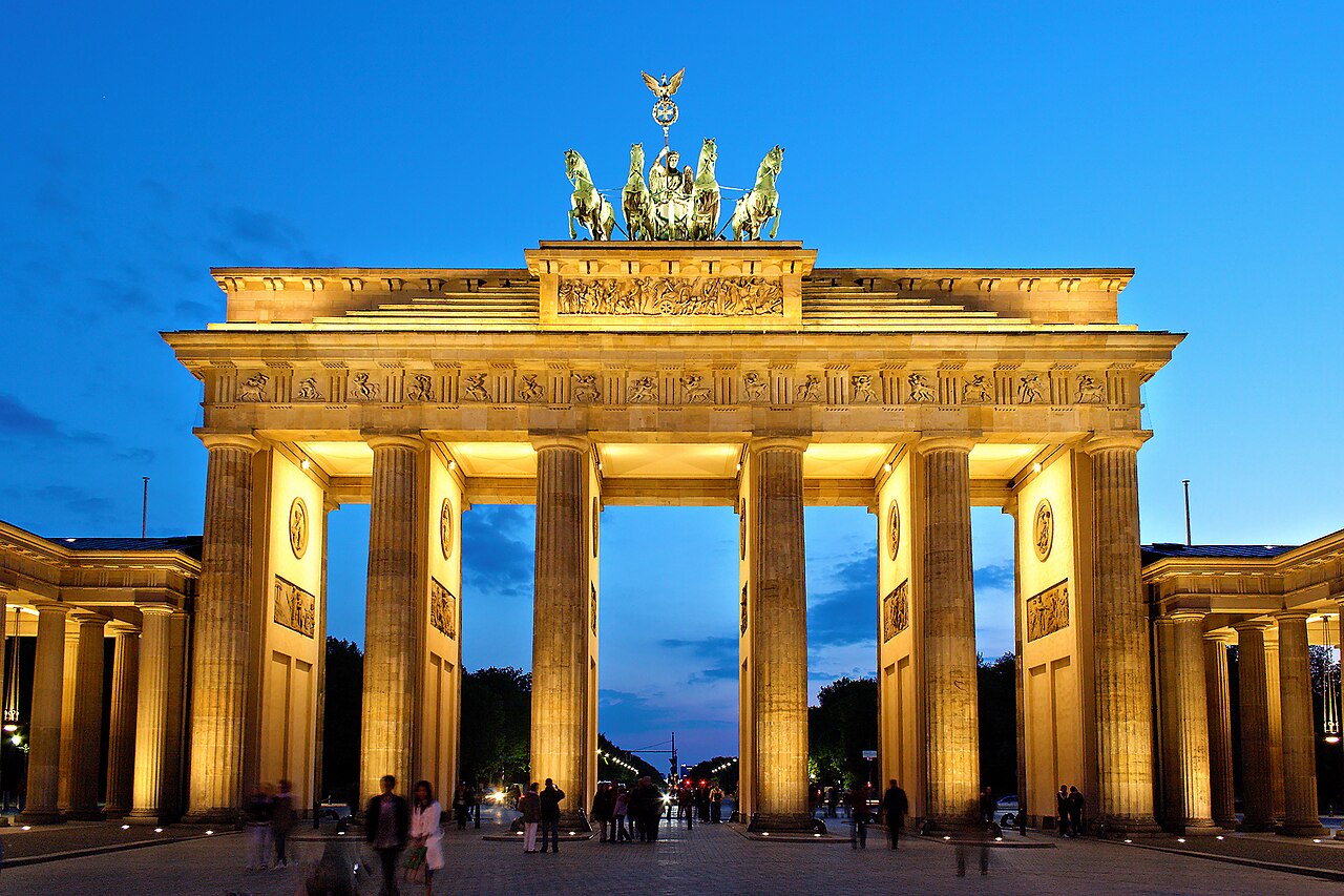 Berlin's Brandenburg Gate lit in gold against a blue evening sky