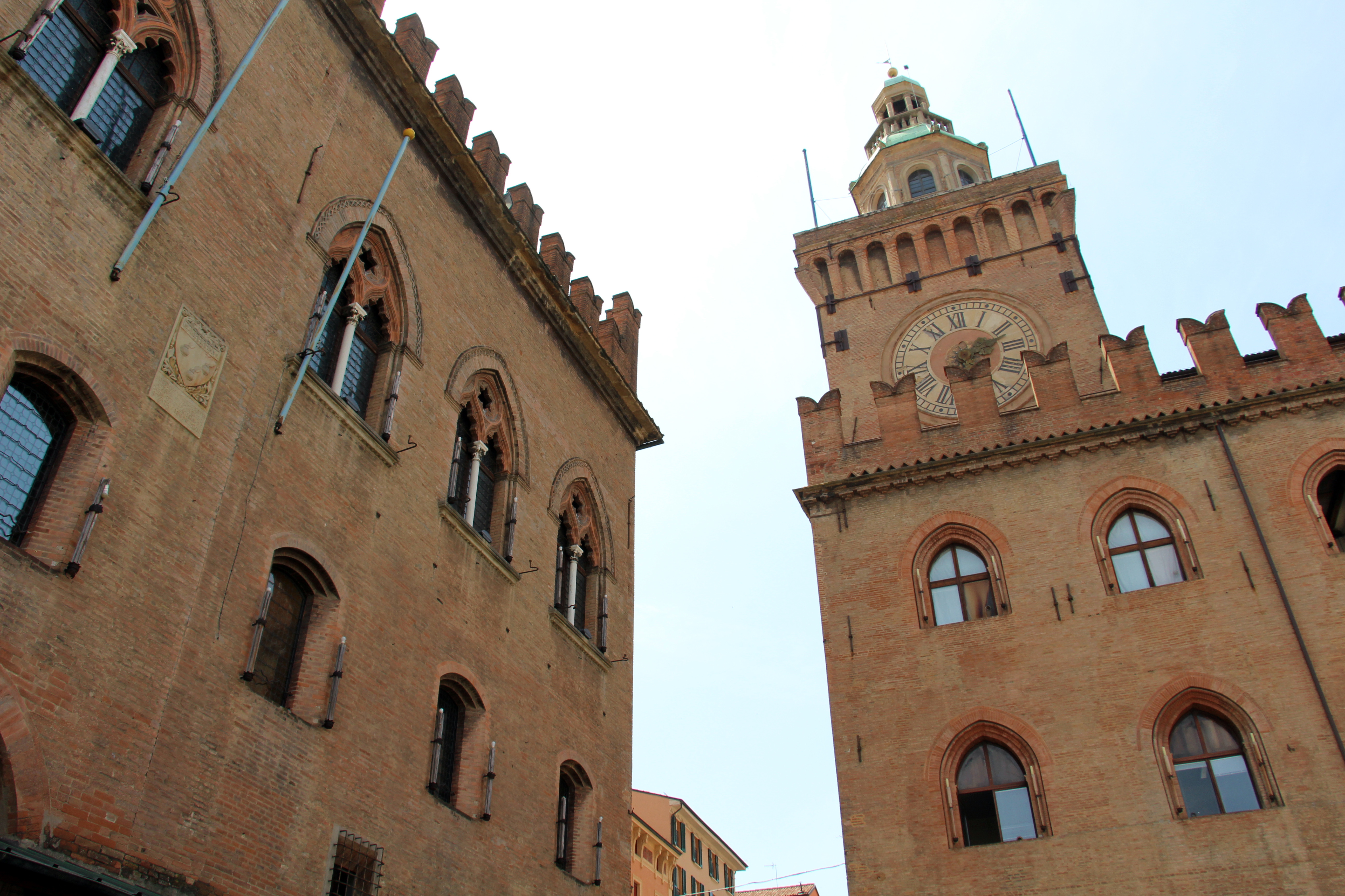 Brick civic buildings and the clock tower beside Piazza Maggiore in Bologna