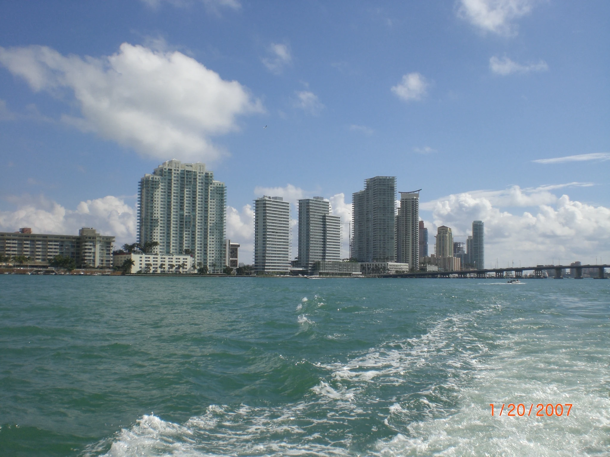 Historical South Beach skyline across Biscayne Bay with towers, bridge and a boat wake