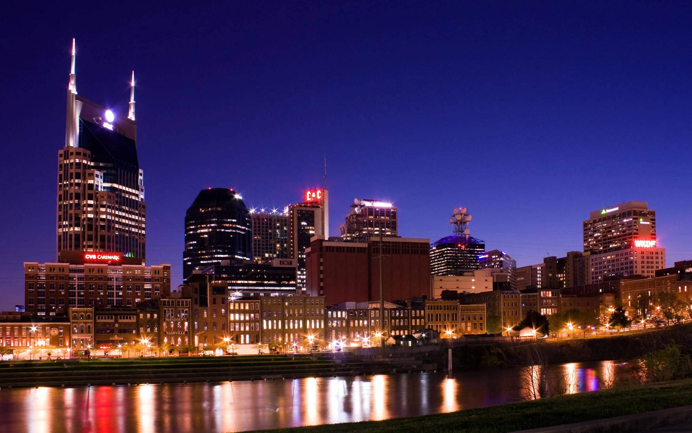 Historical Nashville skyline at night across the Cumberland River with lights reflected on water