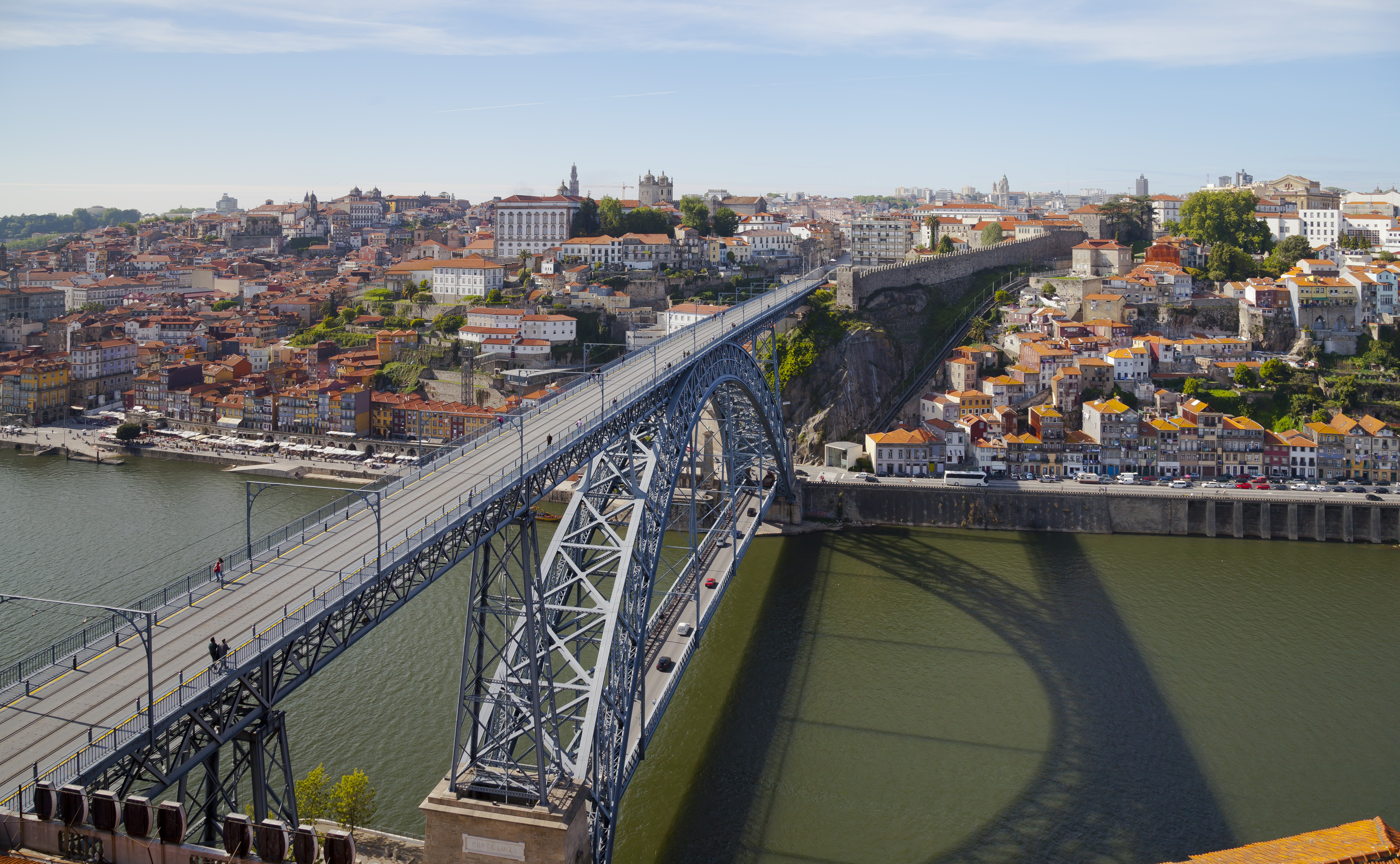 The iron arch and two levels of Dom Luís I Bridge across the Douro, with Porto’s riverside buildings and red roofs beyond