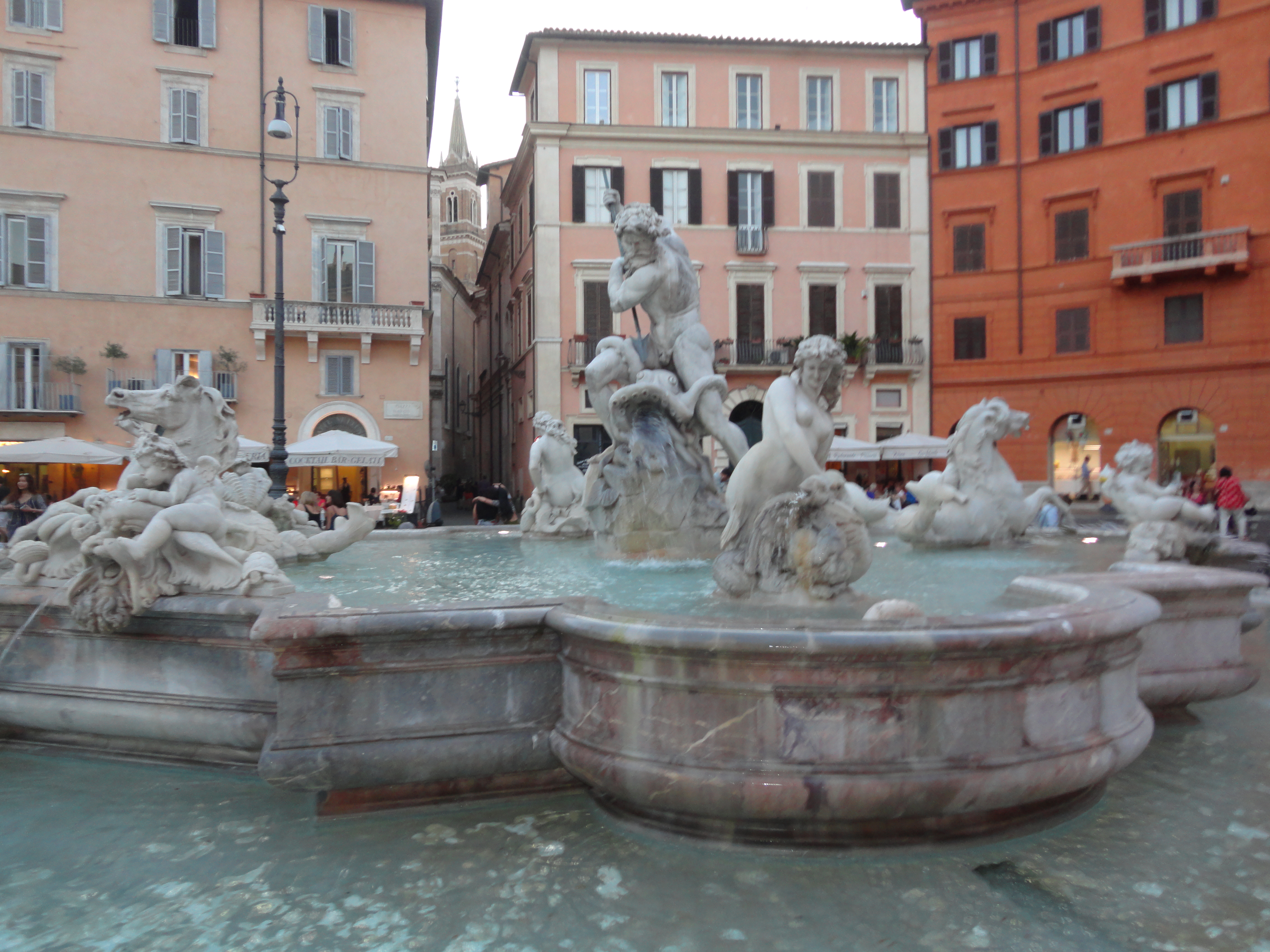 Marble fountain figures and basin with pastel facades in Piazza Navona, Rome