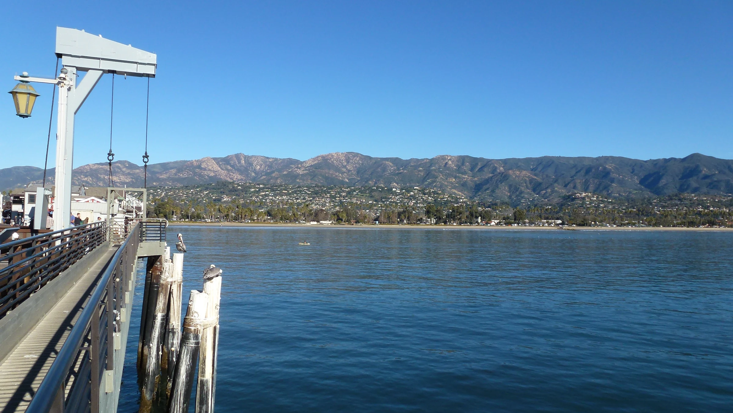 Santa Barbara waterfront backed by low-rise buildings and mountains, seen across the water from Stearns Wharf
