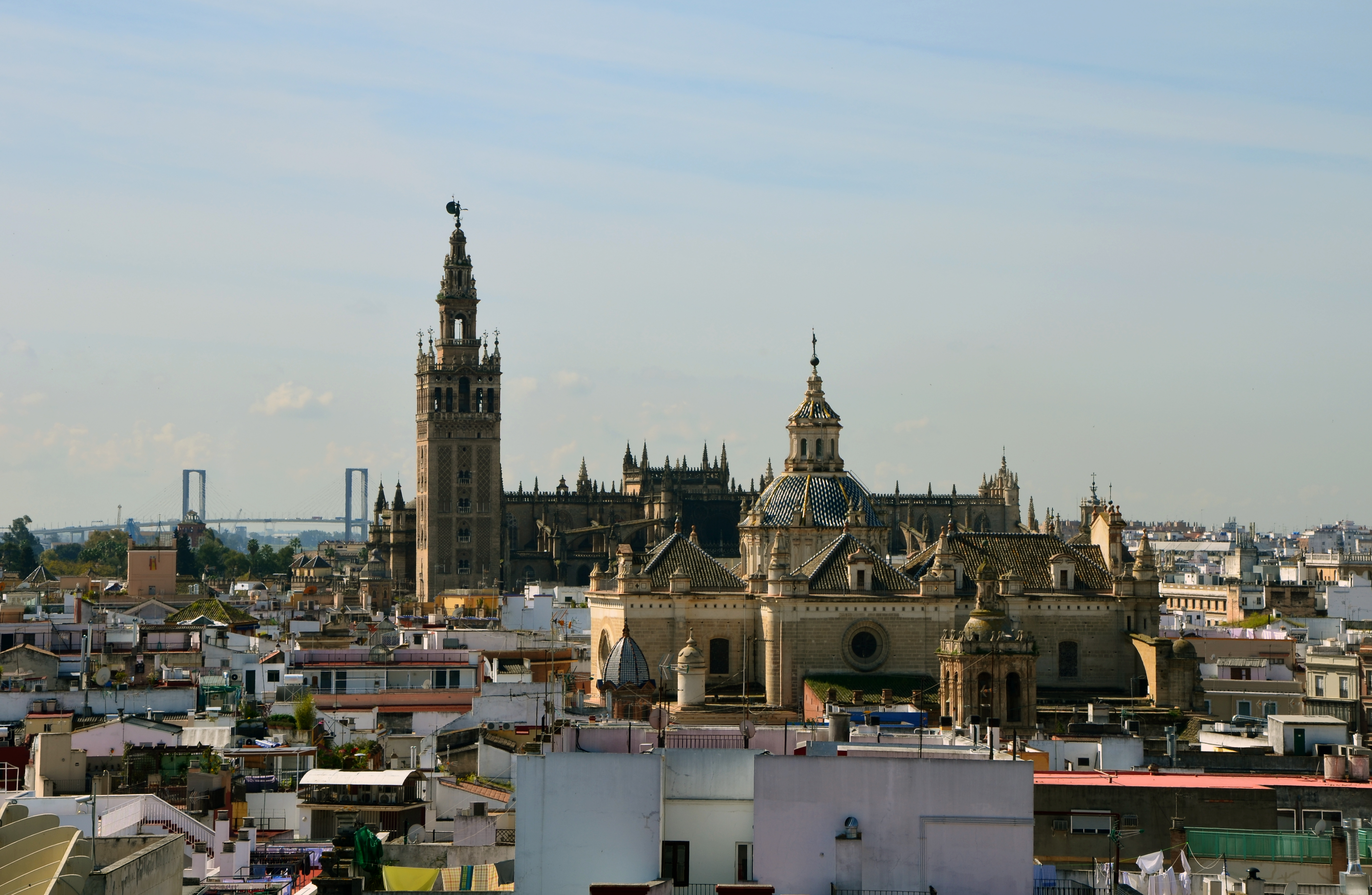 Seville rooftops and the dome of Divino Salvador, with the cathedral and Giralda behind beneath a pale sky