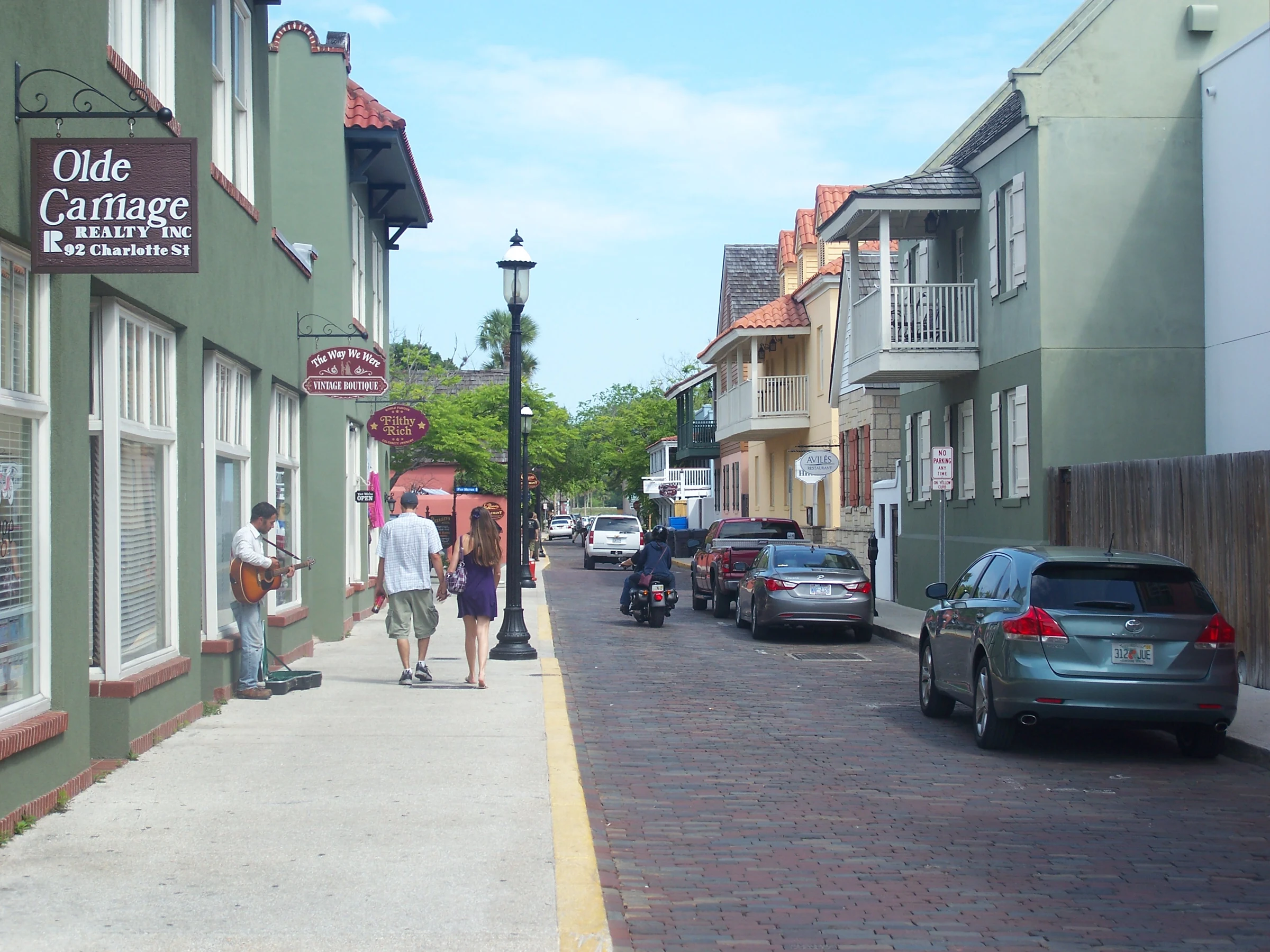 Historical Charlotte Street in St Augustine with low-rise shops, balconies, parked cars and pedestrians