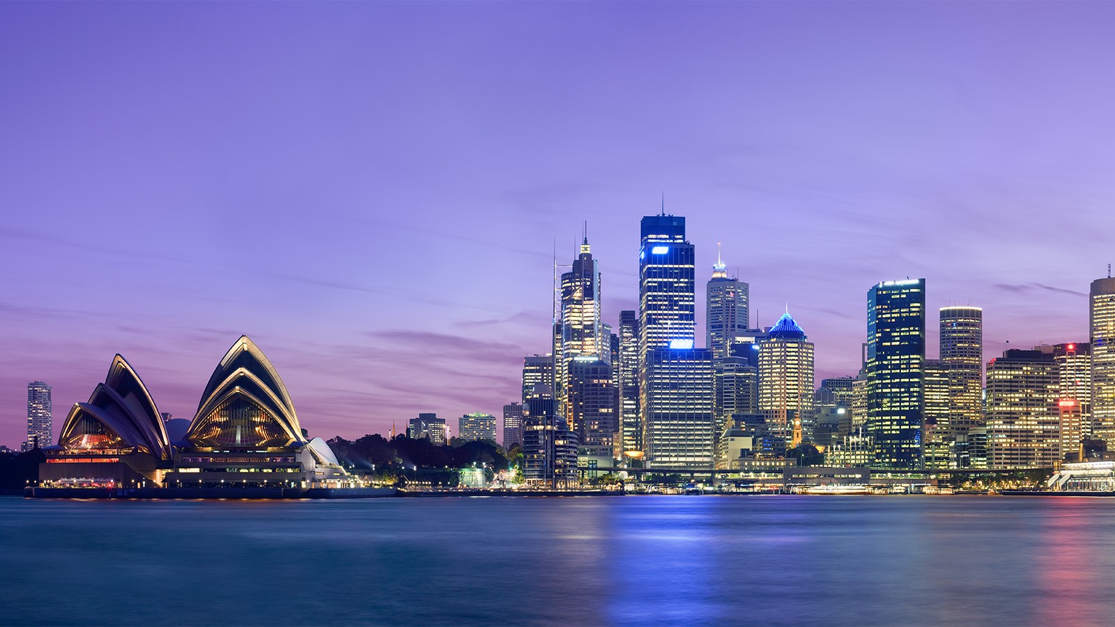 The Sydney Opera House and city skyline seen across the harbour at dusk