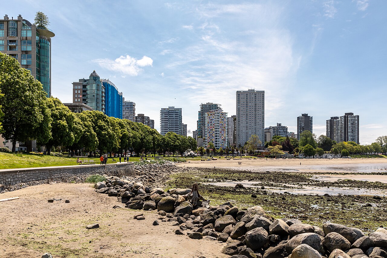 English Bay beach and waterfront buildings in Vancouver with trees beside the shore